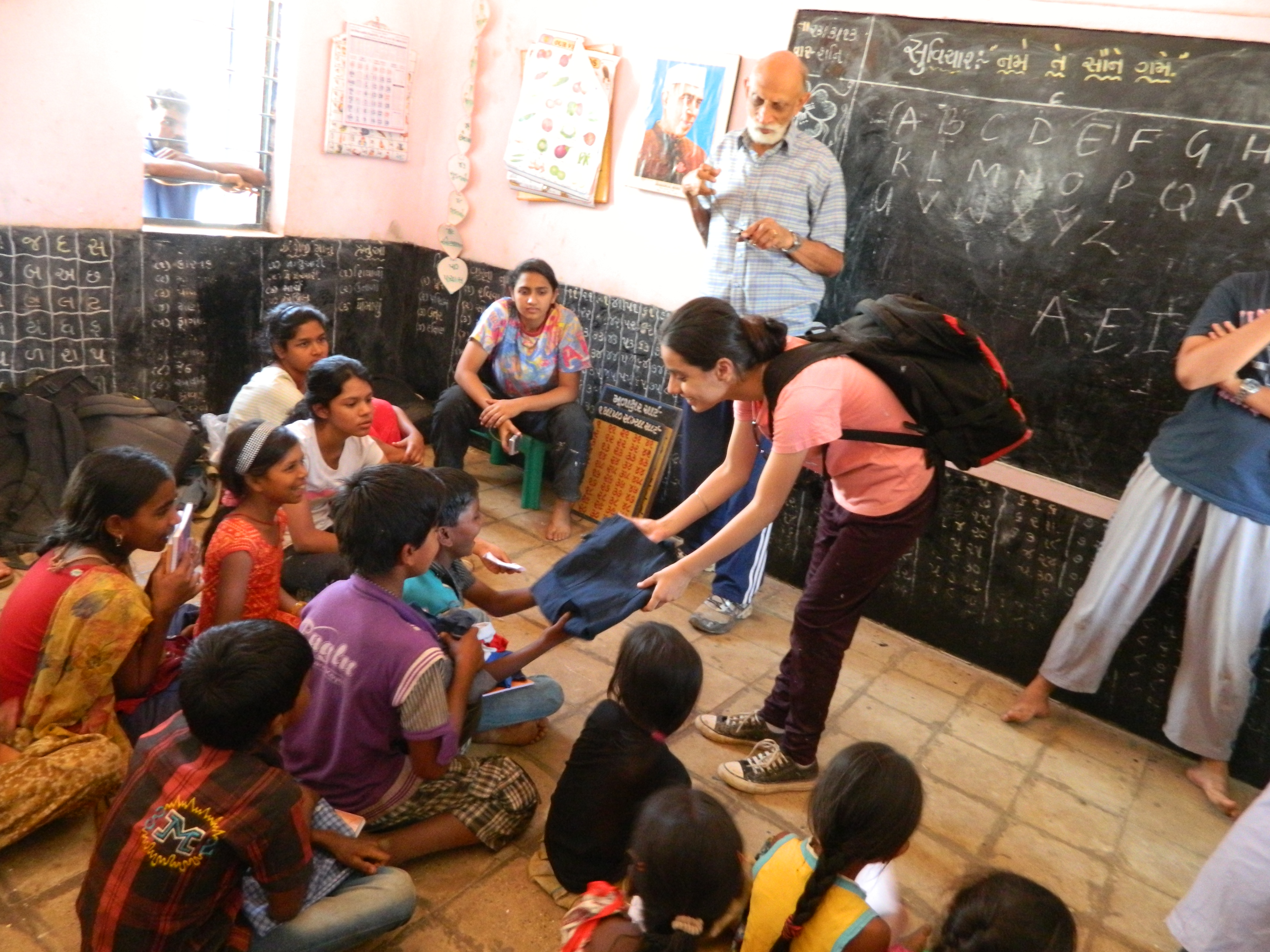 A student sharing clothes with children in a village classroom