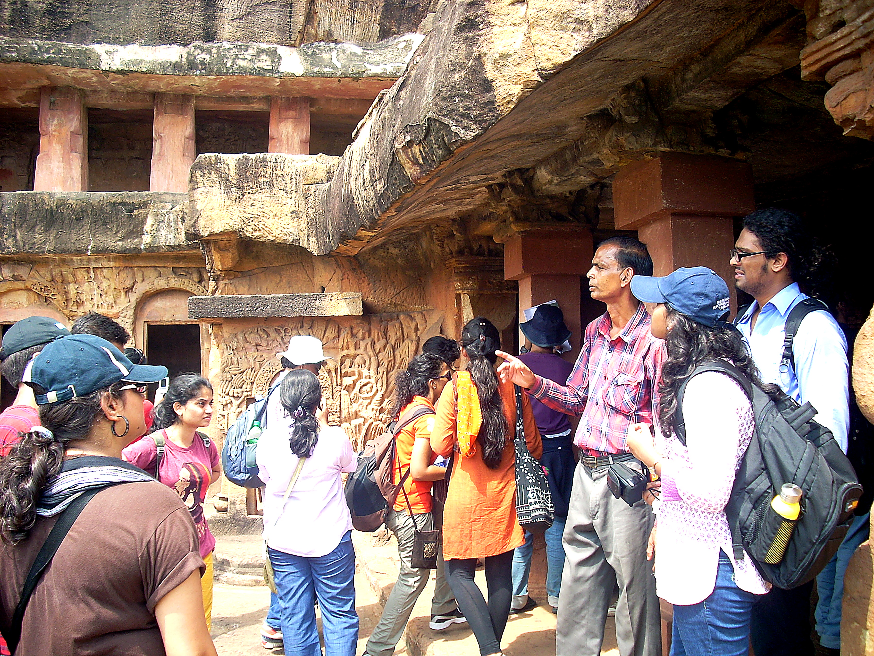 Guide explaining rock-cut caves to students
