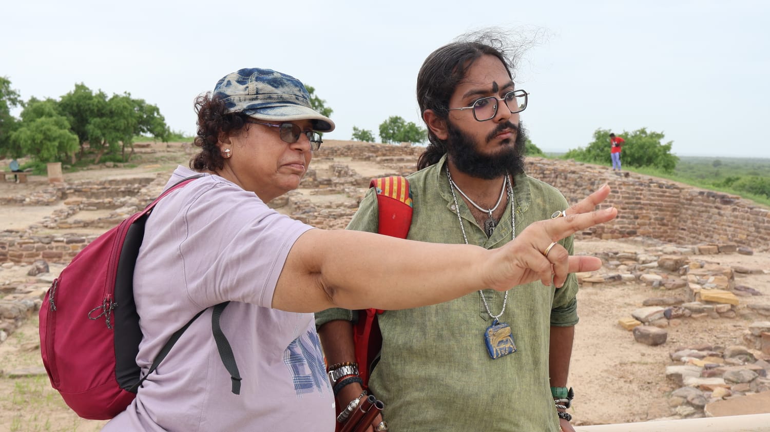 A facilitator pointing out excavated ruins to a student at the site