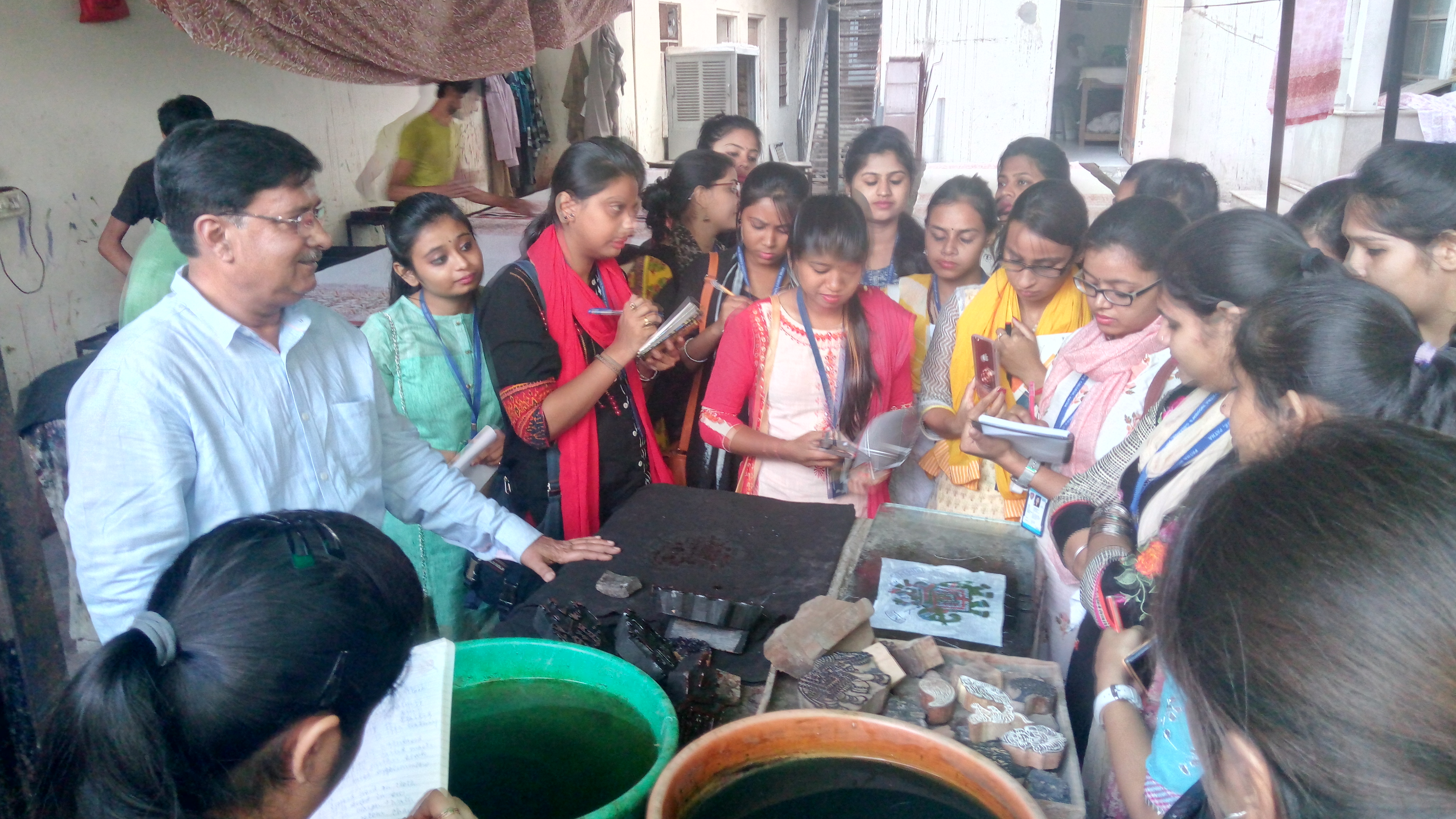 Students studying wooden printing blocks and dyes on a field visit