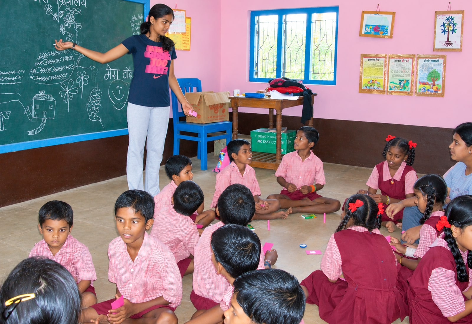 A student teaching children gathered around a chalkboard