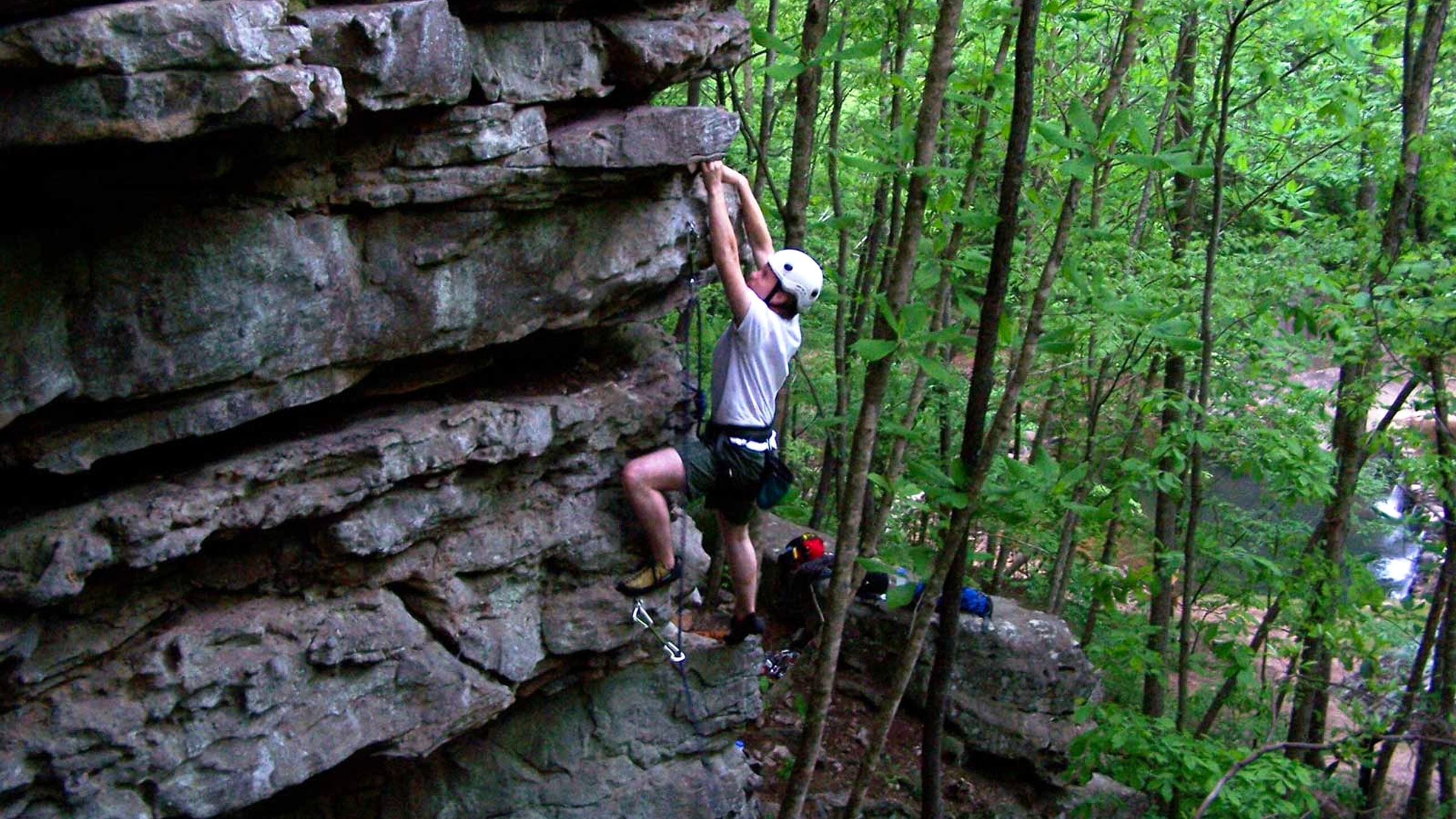 Students rock climbing beside a forest waterfall